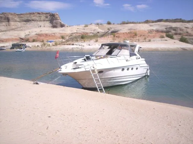 Slide: The Image of A 2001 Regal Commodore 4160 yacht anchored on a sandy beach with rocky cliffs. - 8