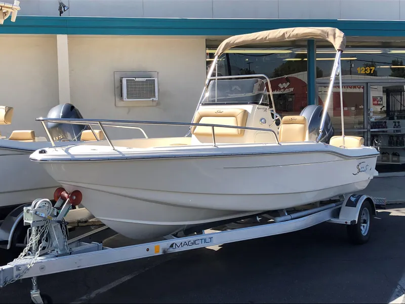 The Image of 2024 Scout 175 Sportfish boat on a trailer outside a store. - 0