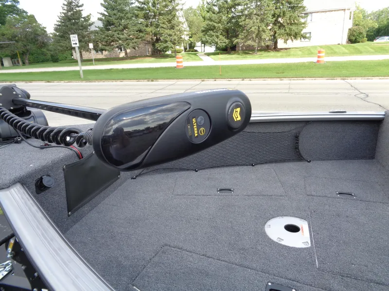 Slide: The Image of 2024 Lund 1875 Impact XS boat interior with trolling motor, gray carpet, and outdoor setting. - 17