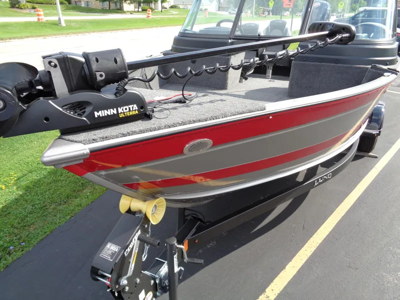 Slide: The Image of 2024 Lund 1875 Impact XS boat with Minn Kota Ulterra motor, parked on a trailer. - 18