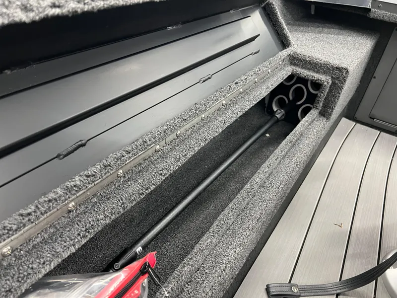 Slide: The Image of Vexus ADX180 2024 boat interior storage compartment with rod holders and carpeted finish. - 21