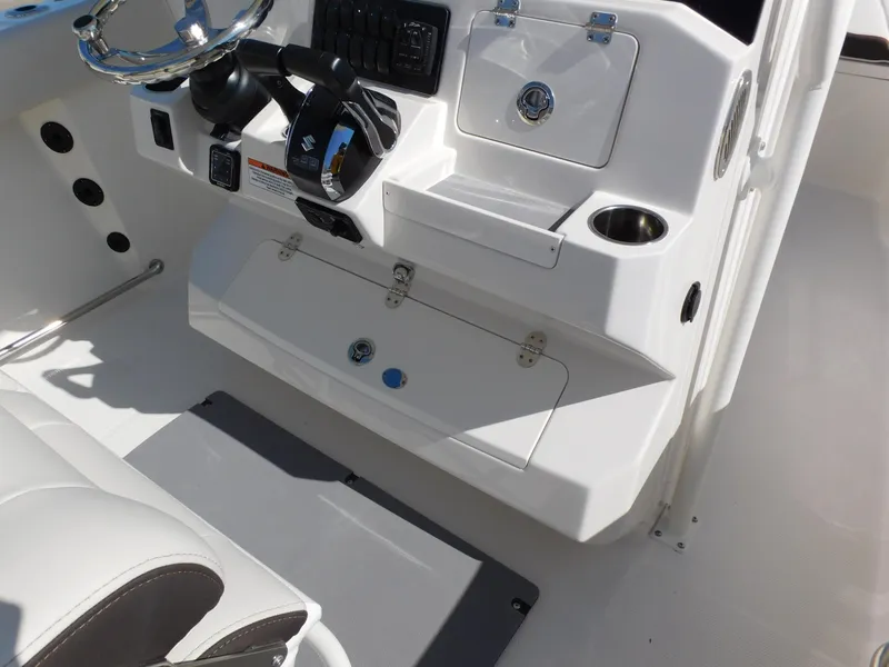 Slide: The Image of 2024 Sailfish 242 CC boat console with steering wheel and storage compartments. - 28