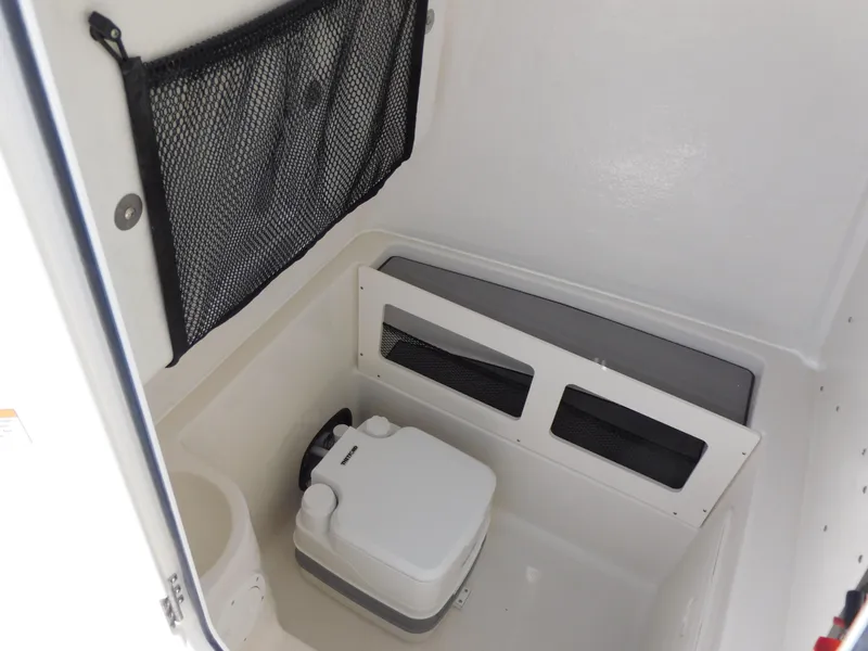 Slide: The Image of 2024 Sailfish 242 CC boat interior with portable toilet and storage net. - 39