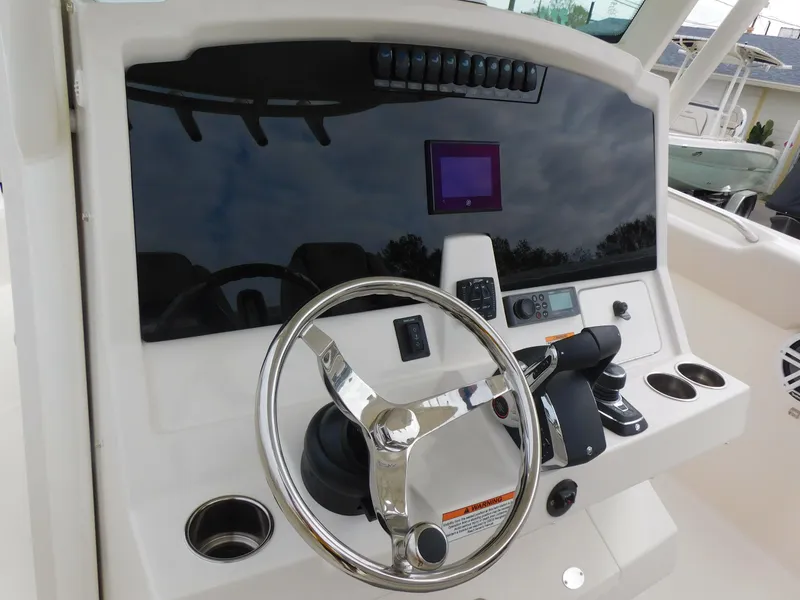 Slide: The Image of 2024 Sailfish 312 CC boat helm with steering wheel and control panel. - 24