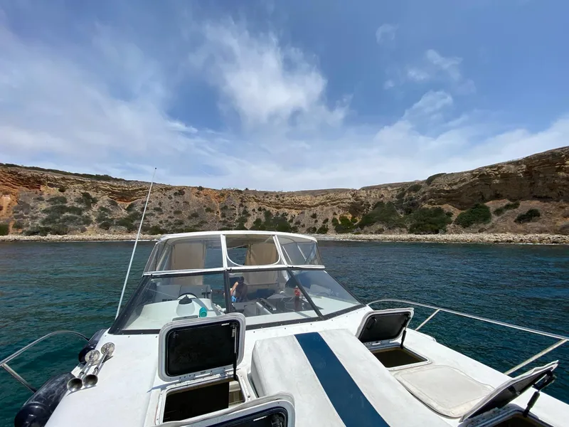 Slide: The Image of 1993 Silverton 38 Express boat anchored near rocky coastline under a partly cloudy sky. - 3