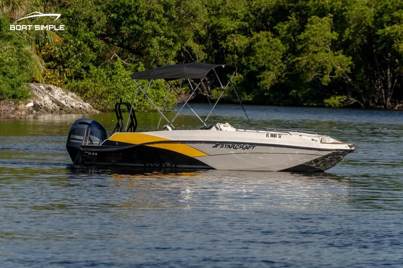 Slide: The Image of 2022 Starcraft SVX 191 OB boat on a calm lake with lush greenery. - 2
