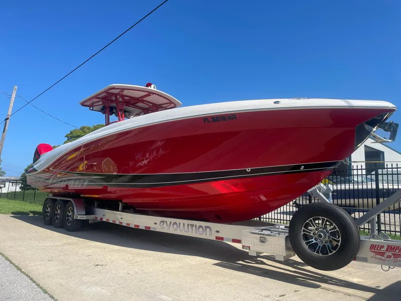 The Image of 2008 Deep Impact 36di red boat on trailer under clear blue sky. - 1