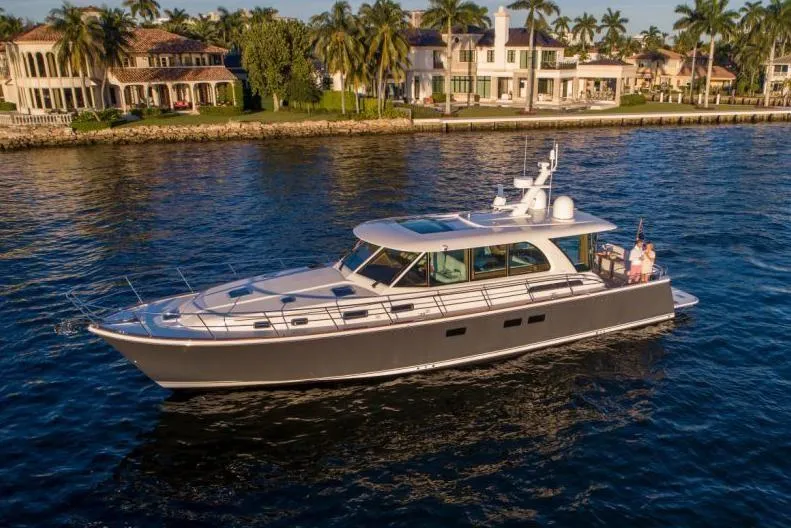 Slide: The Image of 2025 Sabre 58 Salon Express luxury yacht cruising near waterfront homes. - 3