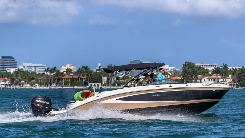 Slide: The Image of 2015 Sea Ray SDX 270 boat cruising on water near coastal city. - 26