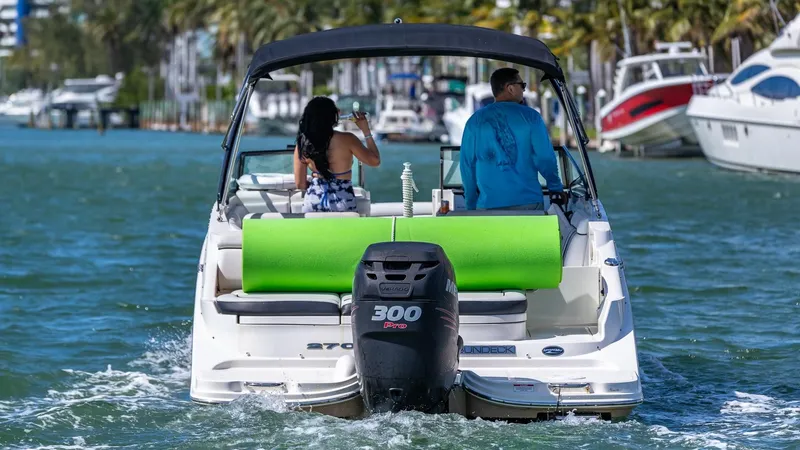 Slide: The Image of 2015 Sea Ray SDX 270 boat cruising with two passengers, green float on deck. - 8