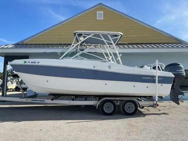 The Image of 2022 World Cat 230 SD boat on a trailer in front of a yellow building. - 22