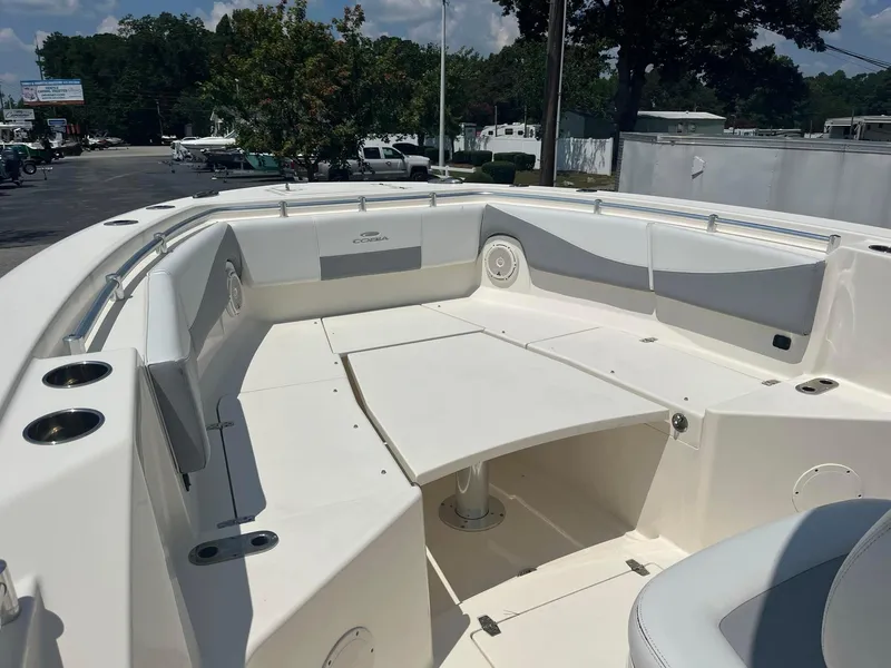 Slide: The Image of 2019 Cobia 320 CC boat interior with seating and table, parked outdoors. - 10