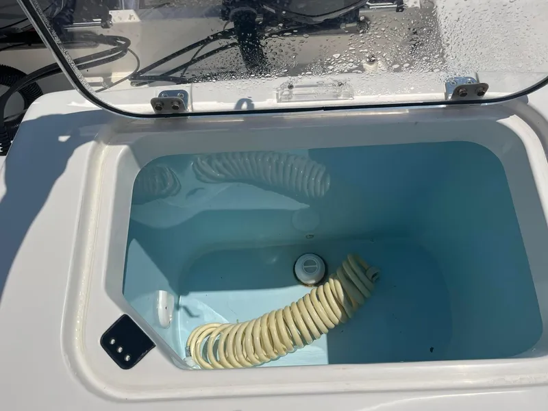 Slide: The Image of Open storage compartment on 2019 Cobia 320 CC boat with coiled hose inside. - 13