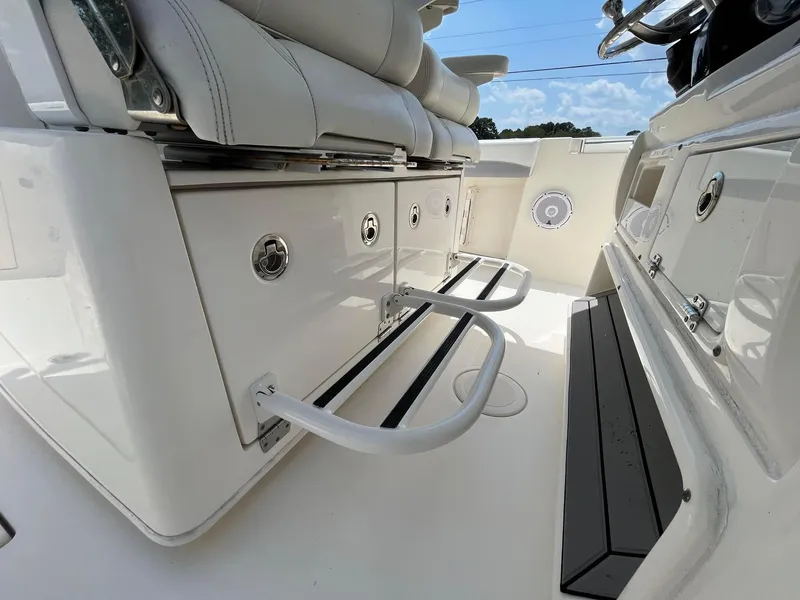 Slide: The Image of 2019 Cobia 320 CC boat interior with white seating and storage compartments. - 23
