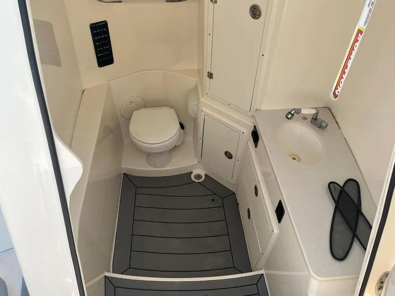 Slide: The Image of 2019 Cobia 320 CC boat bathroom with toilet, sink, and storage cabinets. - 29
