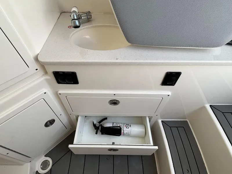 Slide: The Image of 2019 Cobia 320 CC boat interior with sink and fire extinguisher drawer. - 33