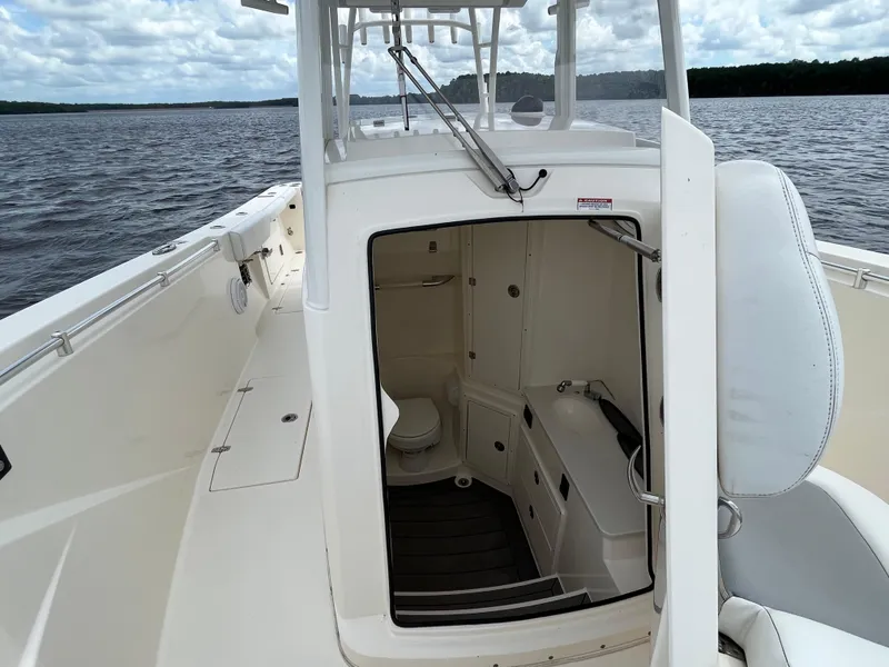 Slide: The Image of 2019 Cobia 320 CC boat interior with open cabin door on the water. - 37