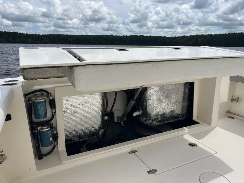Slide: The Image of 2019 Cobia 320 CC boat storage compartment with equipment, under a cloudy sky. - 39