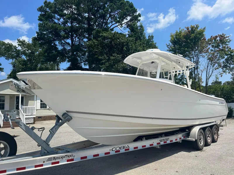 Slide: The Image of 2019 Cobia 320 CC boat on trailer, parked outdoors, sunny day. - 4
