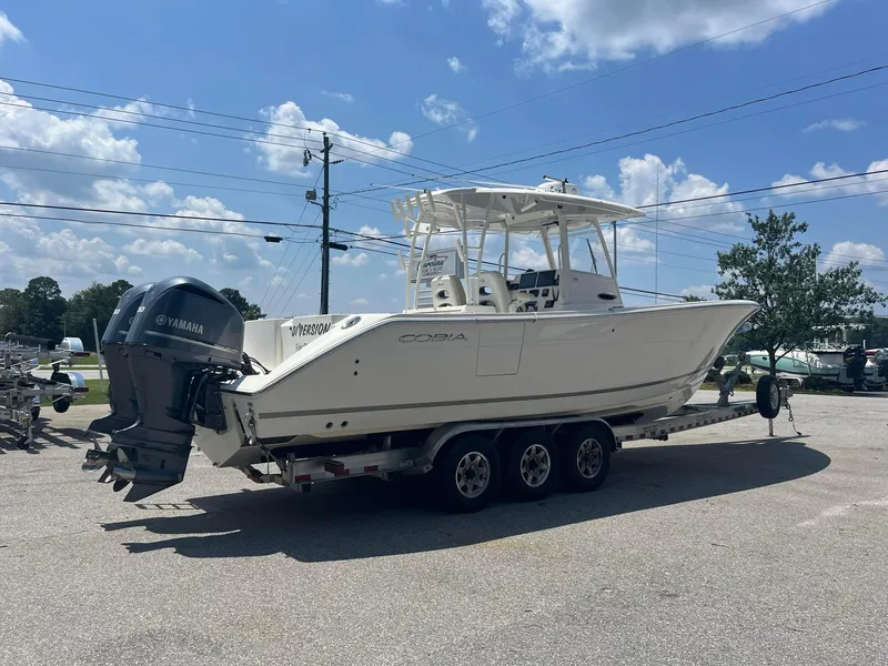 Slide: The Image of 2019 Cobia 320 CC boat on trailer under a sunny sky. - 5