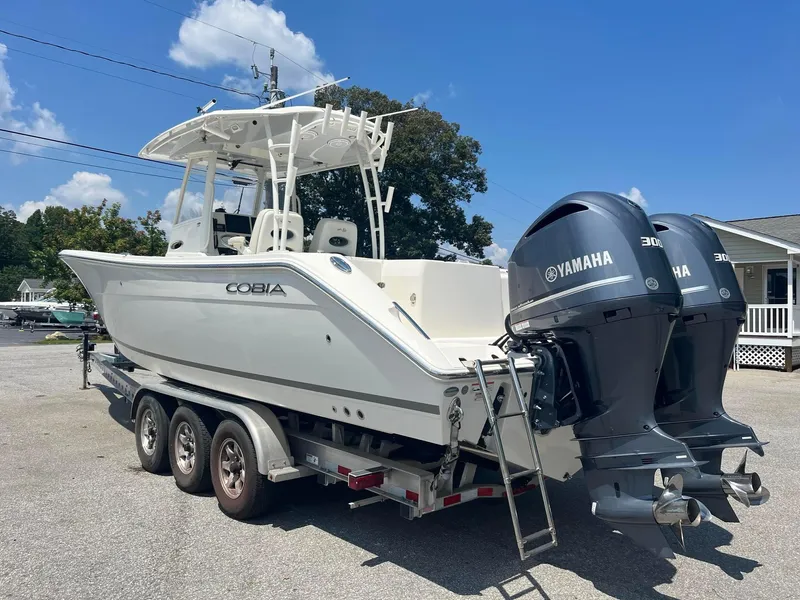 Slide: The Image of 2019 Cobia 320 CC boat on trailer with twin Yamaha engines, parked outdoors. - 6