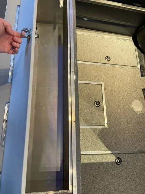 Slide: The Image of 2024 Spartan 185 Astoria boat storage compartment with hand opening the lid. - 10