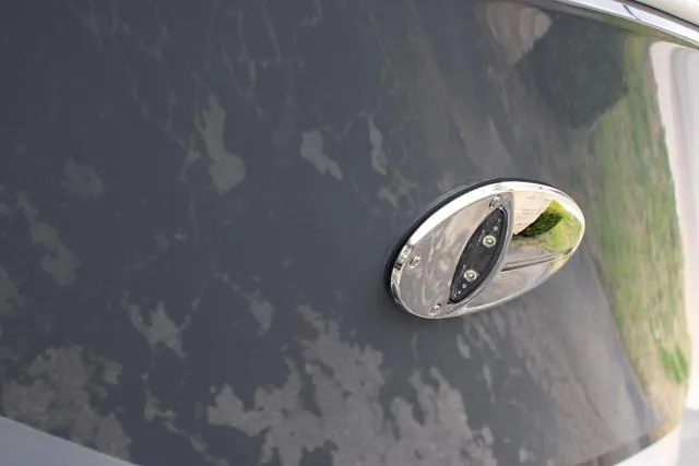 Slide: The Image of 2024 Regal LS6 Surf boat detail with chrome accent on dark hull. - 15