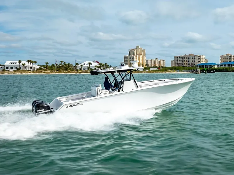 Slide: The Image of 2020 SeaHunter 35 Tournament boat cruising on water near coastal buildings. - 14