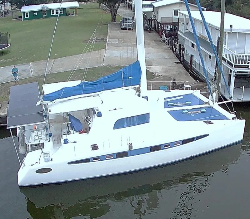 Slide: The Image of Catamaran Dolphin 43, 2002 model, docked near waterfront homes. - 13