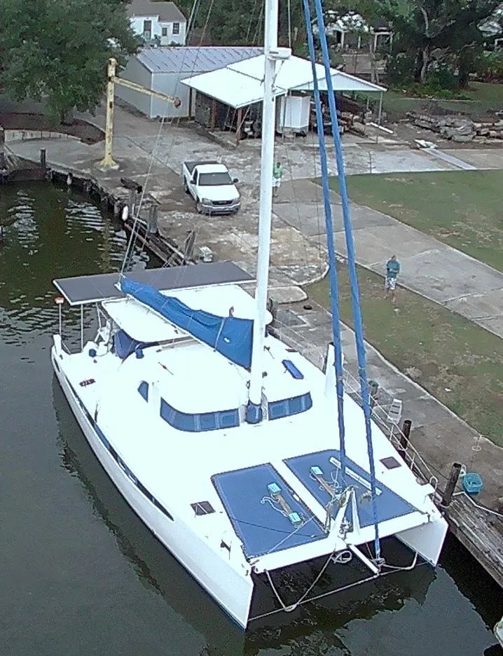 Slide: The Image of 2002 Dolphin 43 catamaran docked near a waterfront with a parked vehicle. - 16