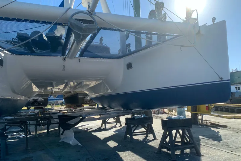 Slide: The Image of Catamaran Dolphin 43, 2002 model, on dry dock for maintenance under bright sunlight. - 23