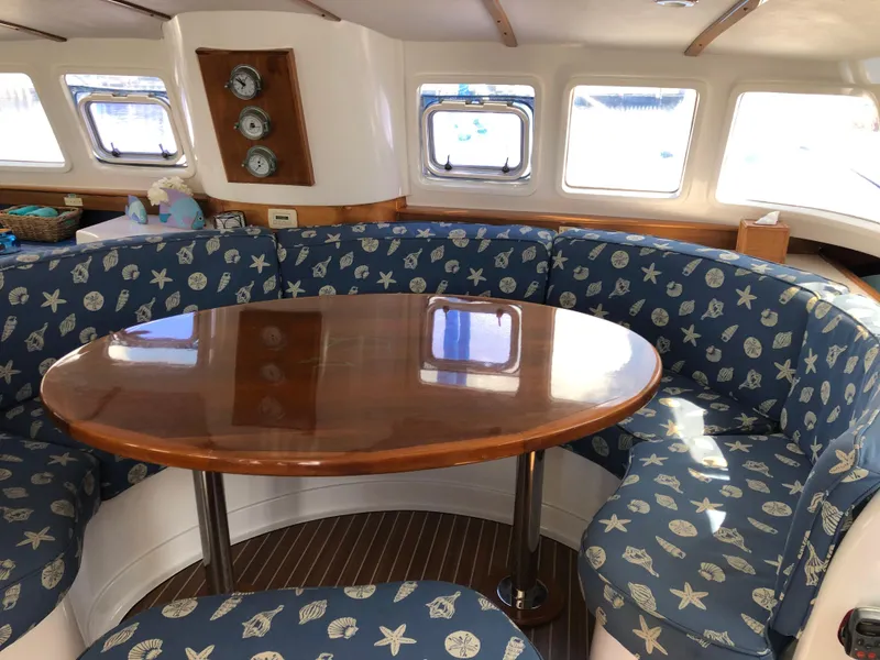 Slide: The Image of Luxurious Dolphin 43 yacht interior with round wooden table and patterned blue seating, 2002 model. - 27