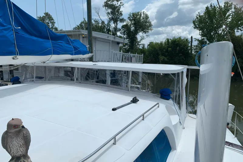 Slide: The Image of 2002 Dolphin 43 sailboat with blue sails, docked near trees and a house. - 30