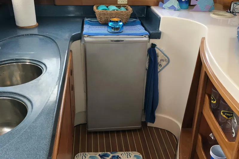 Slide: The Image of Compact kitchen area in a 2002 Dolphin 43 boat with a small fridge. - 32