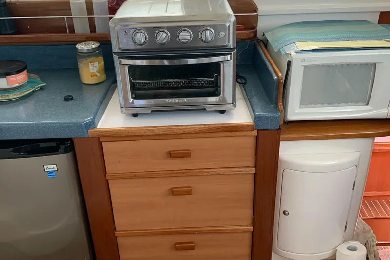 Slide: The Image of Kitchen area with toaster oven, microwave, and wooden drawers on a Dolphin 43 boat. - 33