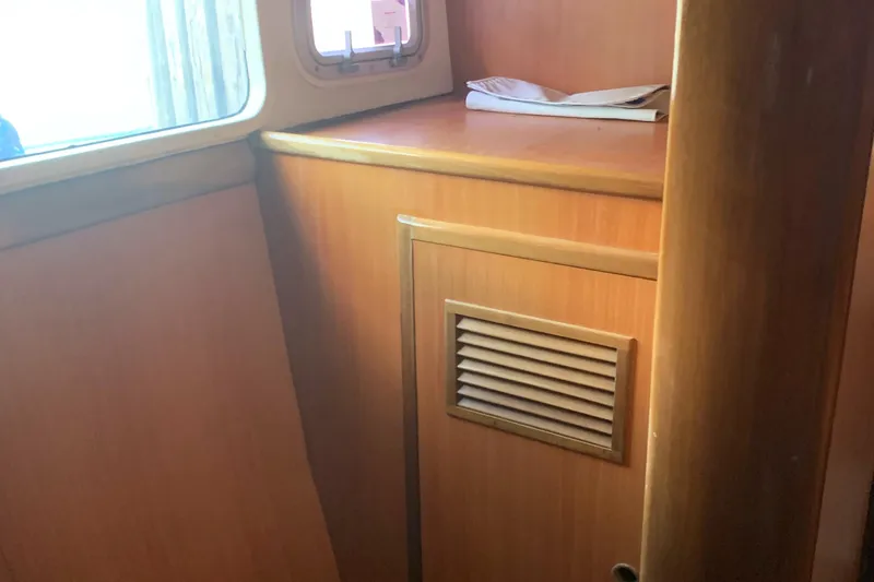 Slide: The Image of Interior of a 2002 Dolphin 43 boat with wooden cabinetry and a small window. - 36