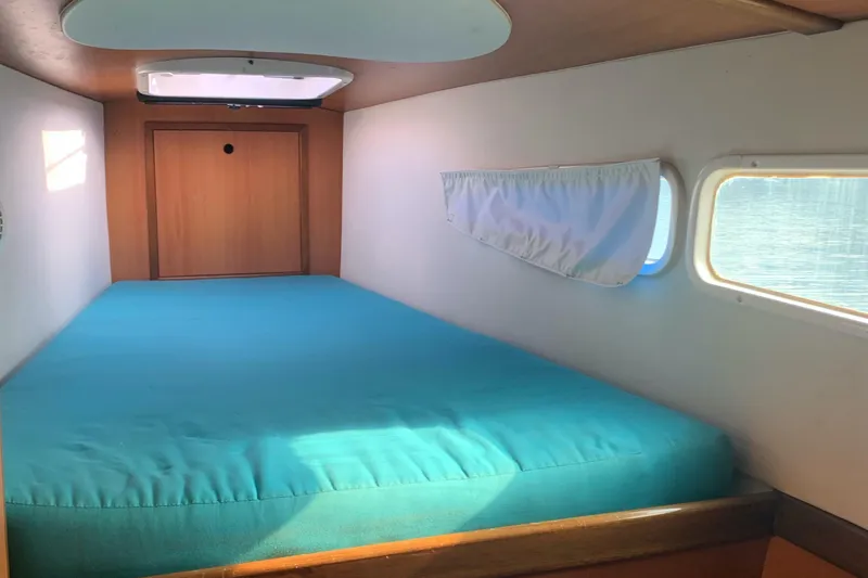 Slide: The Image of Cozy cabin interior of 2002 Dolphin 43 yacht with turquoise bedding and porthole windows. - 39