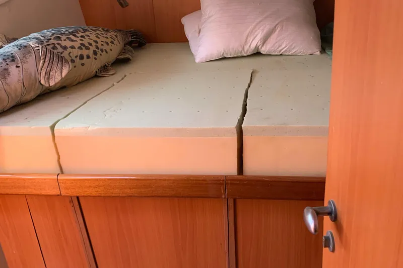 Slide: The Image of Boat cabin with split mattress, wooden frame, and decorative pillow. Dolphin 43, 2002 model. - 40