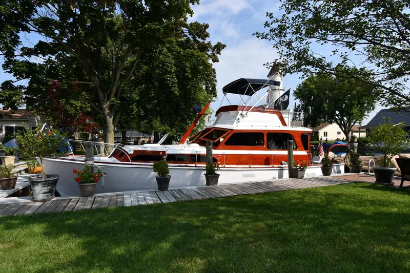 The Image of 1964 Egg Harbor 37 Convertible Sedan docked, surrounded by trees and greenery. - 0