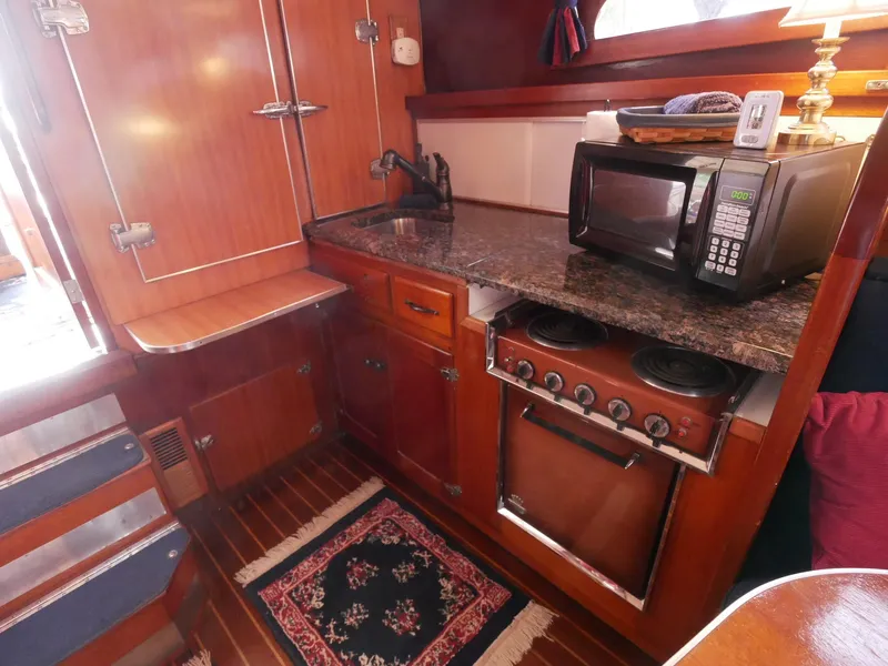 Slide: The Image of 1964 Egg Harbor 37 Convertible Sedan galley with stove, microwave, and wooden cabinetry. - 27