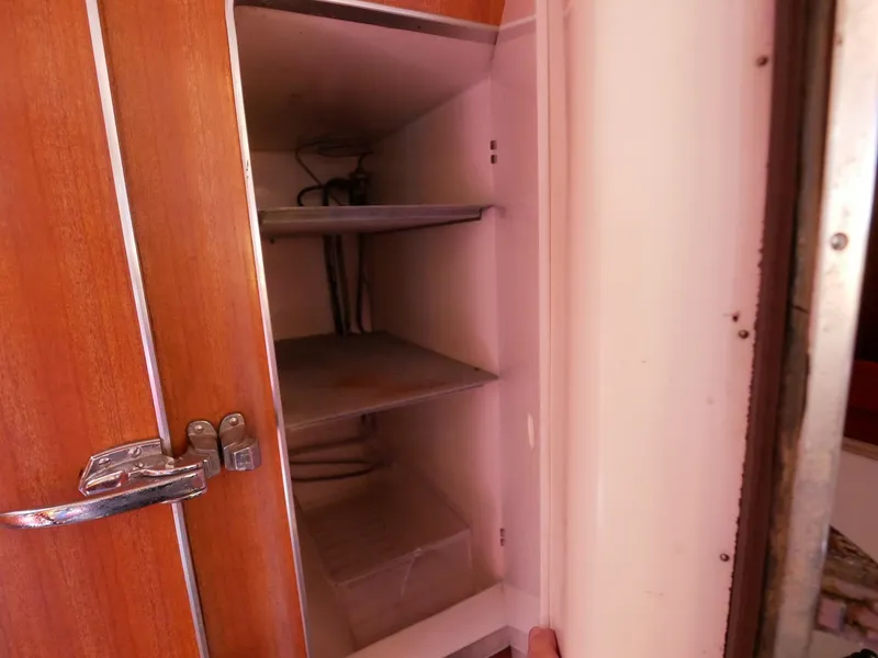 Slide: The Image of 1964 Egg Harbor 37 Convertible Sedan interior storage cabinet with wooden door and metal shelves. - 32