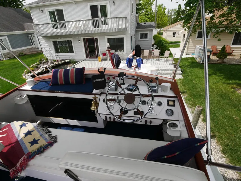 Slide: The Image of 1964 Egg Harbor 37 Convertible Sedan boat interior with steering wheel and residential background. - 39