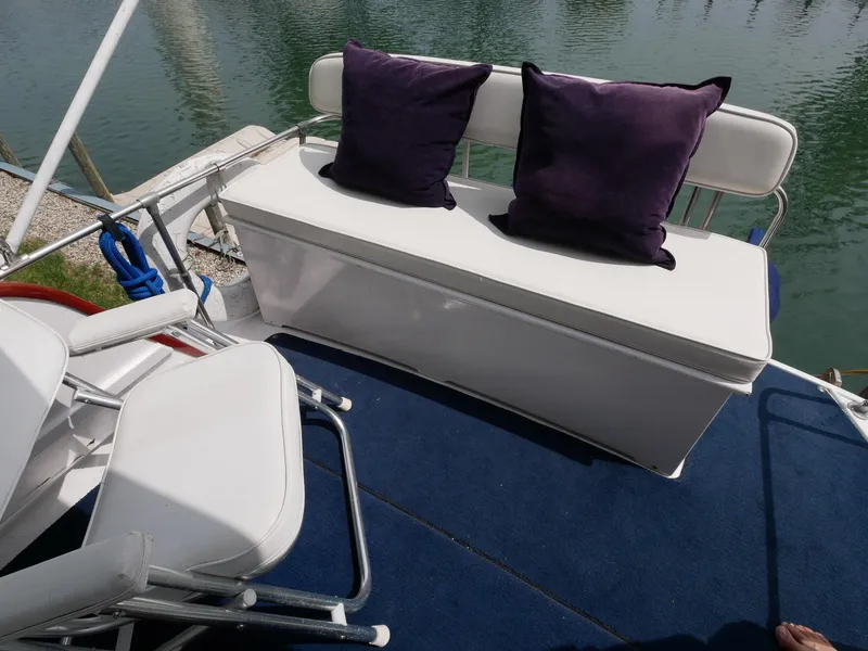 Slide: The Image of 1964 Egg Harbor 37 Convertible Sedan boat seating area with white cushions and purple pillows. - 43