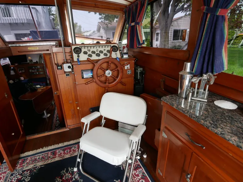 Slide: The Image of 1964 Egg Harbor 37 Convertible Sedan interior with helm, chair, and wooden cabinetry. - 6