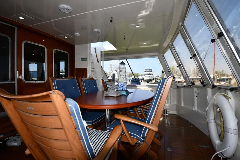 Slide: The Image of 1986 Lowland 64 Pilot House Long Range Motor Yacht interior with dining area and marina view. - 17