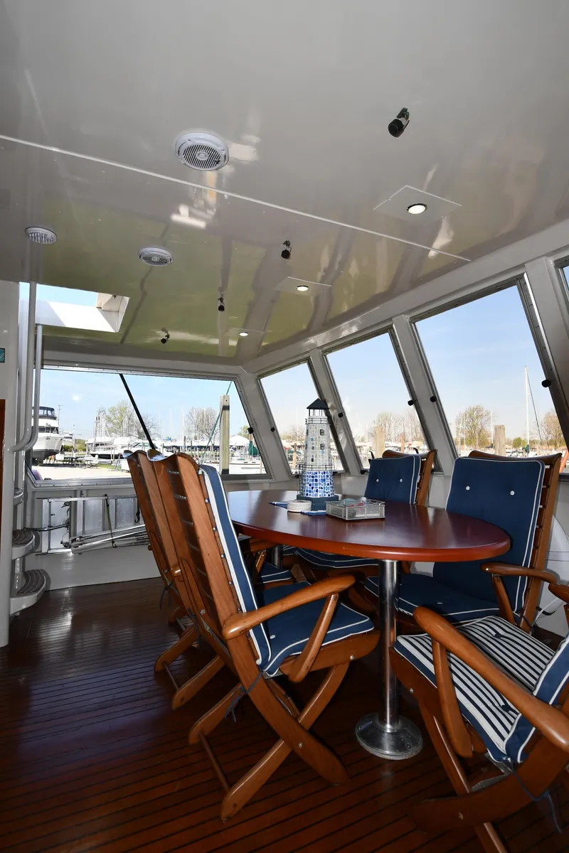 Slide: The Image of 1986 Lowland 64 Pilot House Long Range Motor Yacht interior dining area with wooden table and chairs. - 24