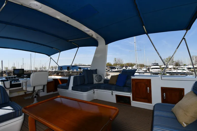 Slide: The Image of Covered deck area of 1986 Lowland 64 Pilot House Long Range Motor Yacht with seating and table. - 46
