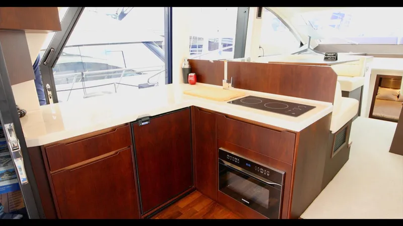 Slide: The Image of Modern kitchen area in the 2024 Galeon 470 Sky yacht with stove, oven, and wooden cabinetry. - 19