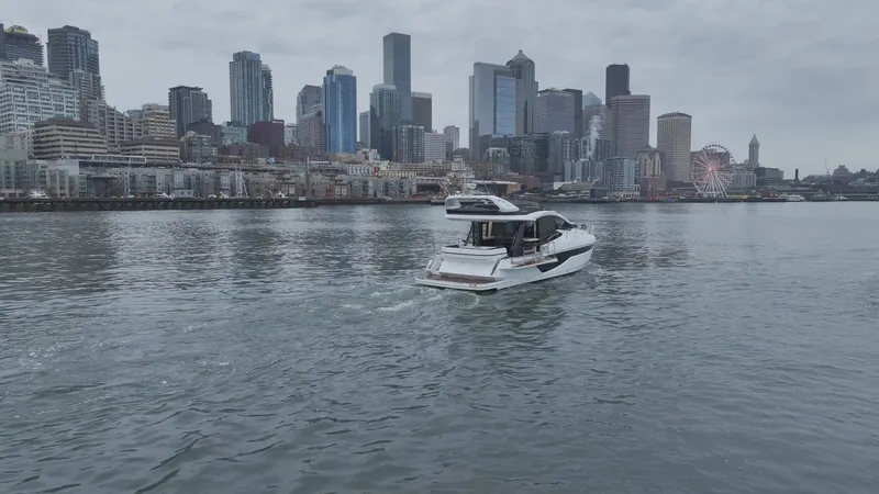 Slide: The Image of 2024 Galeon 470 Sky yacht cruising near city skyline on a cloudy day. - 9