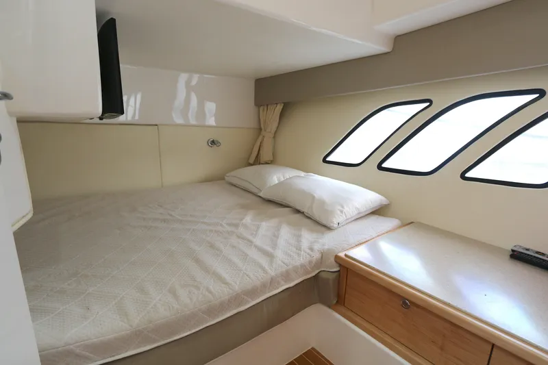 Slide: The Image of 2012 Intrepid 475 Sport Yacht cabin with bed, pillows, and porthole windows. - 11